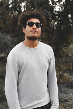 时尚的年轻人在户外戴着太阳镜，自信地在自然背景下摆出姿势