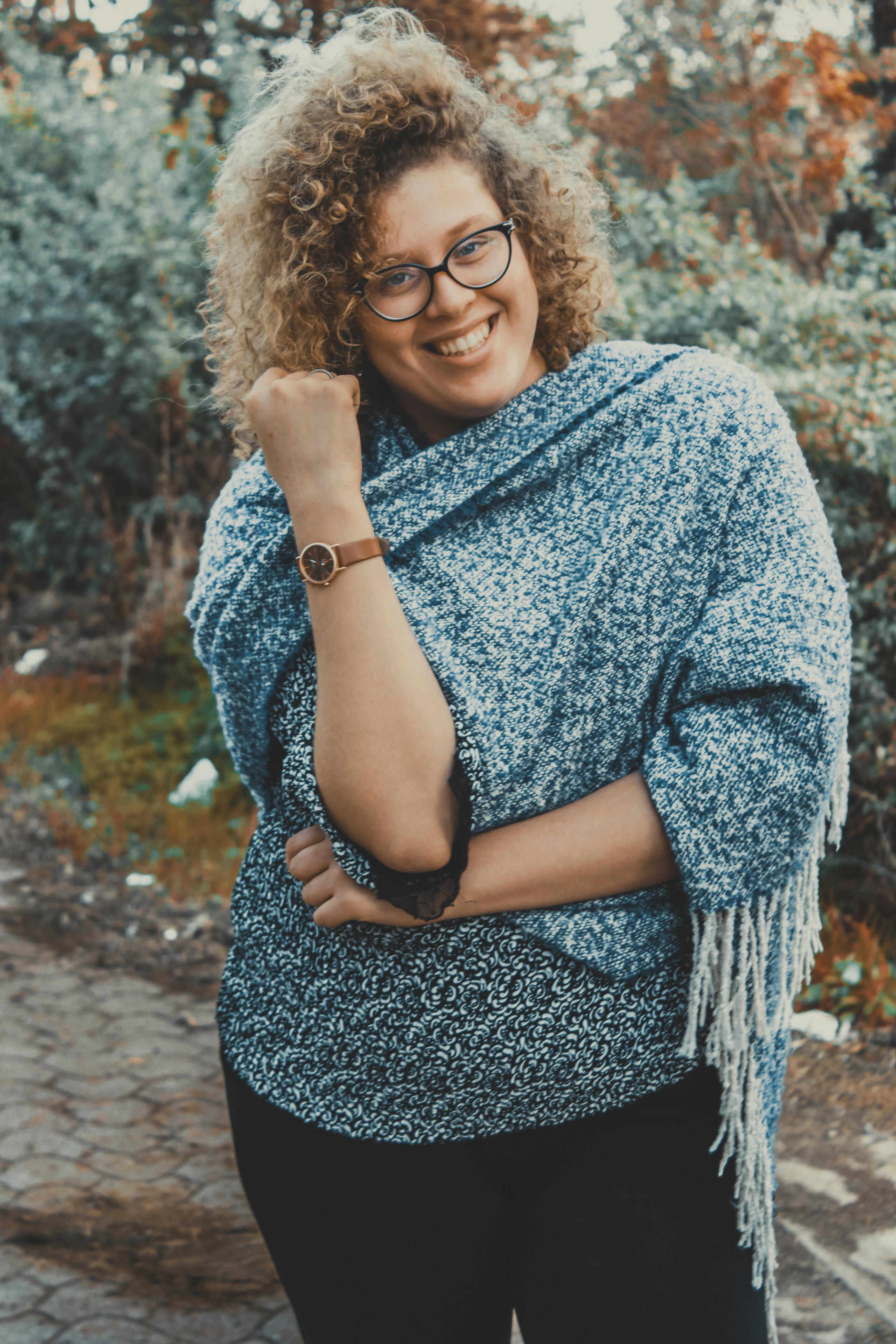 一位戴着眼镜、留着卷发的快乐年轻女子正在公园里享受冬日时光