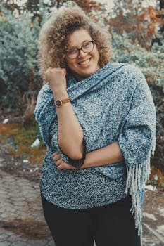 一位戴着眼镜、留着卷发的快乐年轻女子正在公园里享受冬日时光