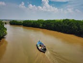 在印度尼西亚克龙乔，一艘渔船航行在风景优美的河流上，四周环绕着郁郁葱葱的森林