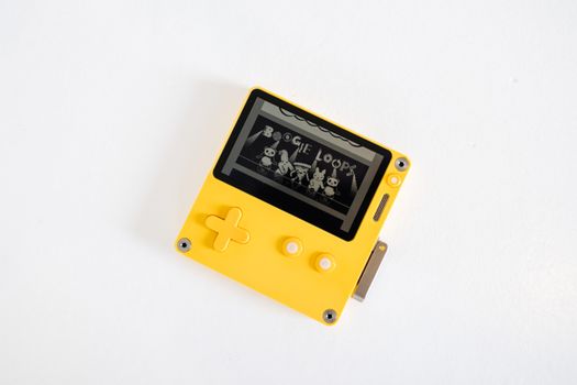Minimalist photo of a yellow retro gaming console against a white background.