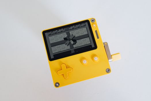 Yellow retro-style gaming console with crank, photographed against a white background.