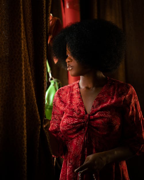 Woman in Red Dress Looking out from behind Curtain