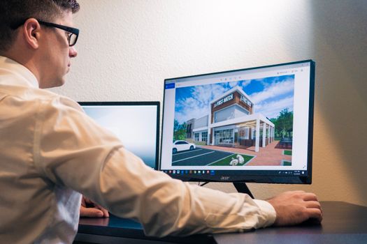 Architect evaluating a building design on a computer screen in an office setting.