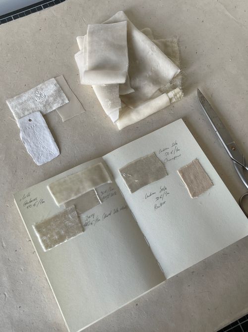 Free Open design journal with fabric swatches and handwritten notes, scissors nearby. Stock Photo