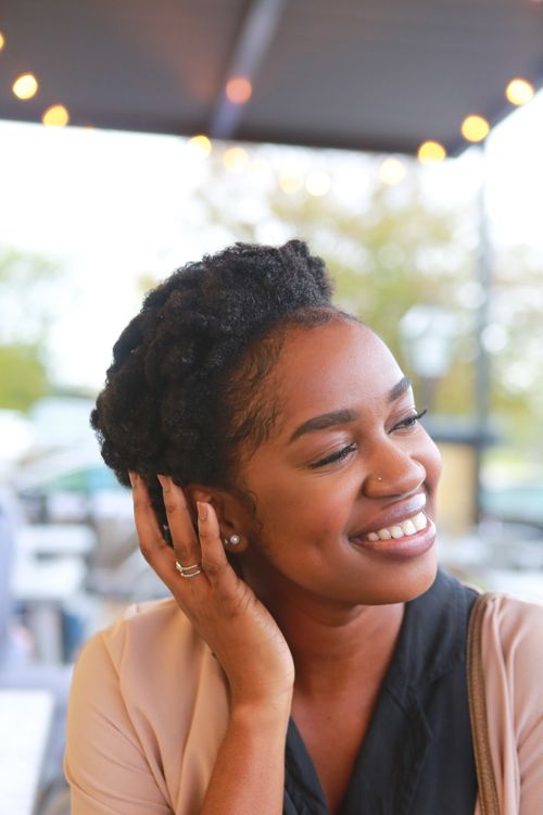 Free A joyful woman smiling brightly while sitting outdoors on a sunny day. Stock Photo