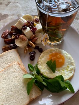 Plate of toast, fried egg, bananas, and tea for a balanced breakfast.