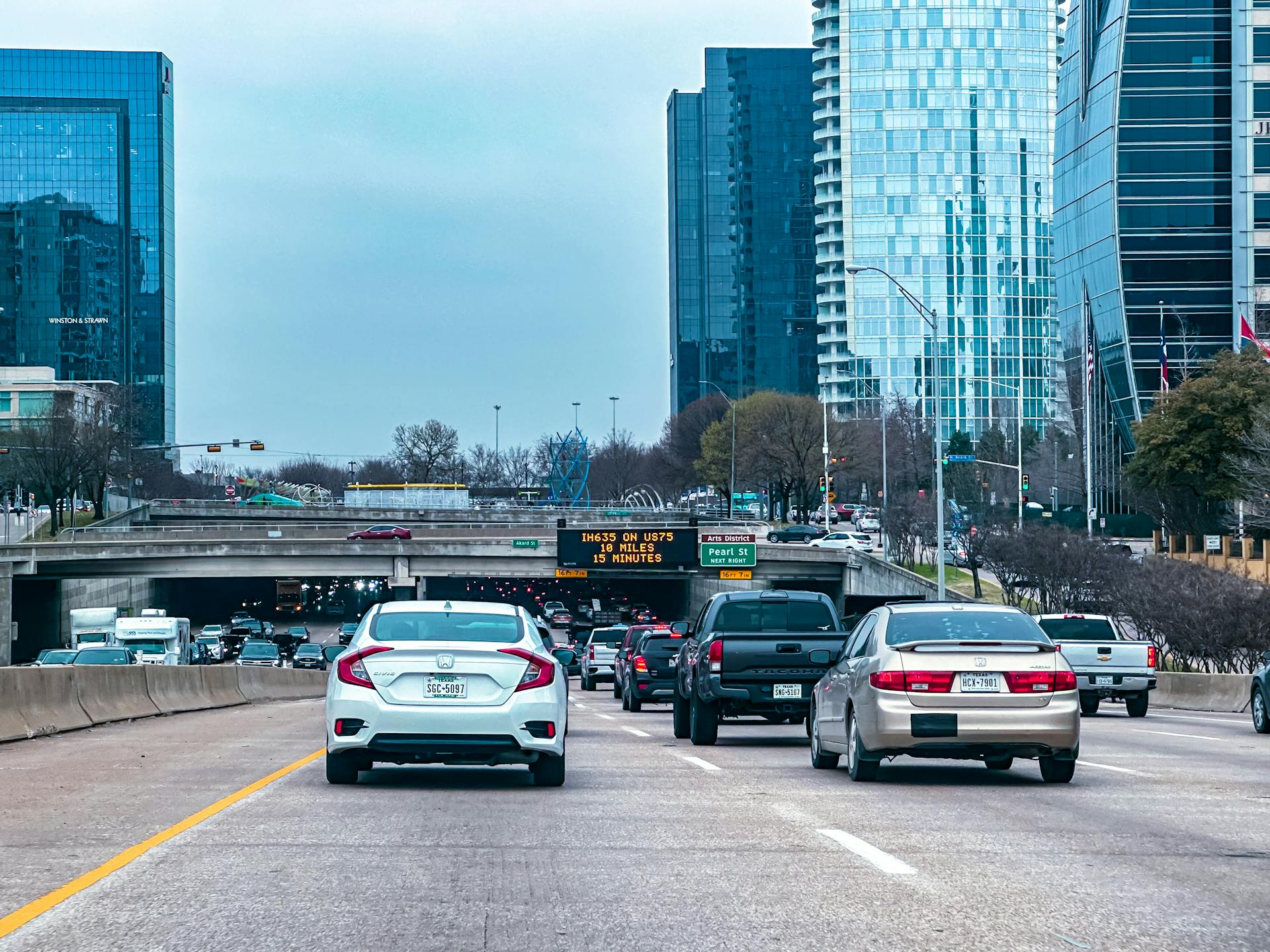 Busy traffic scene on a Dallas highway with skyscrapers in the background.