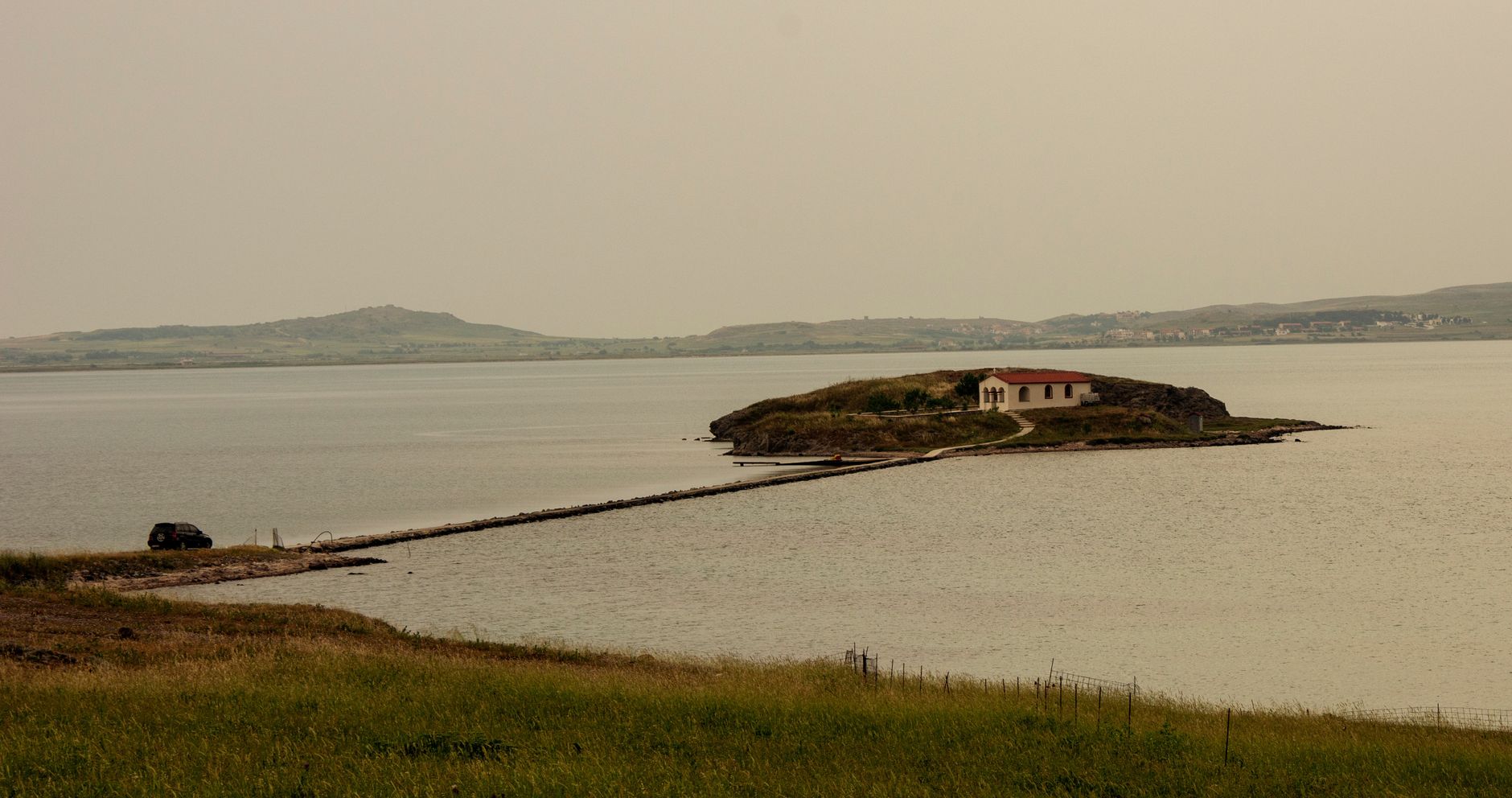 A quiet bay on Lemnos with a single building on the shore and calm water.