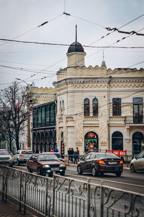 Free Charming city street with historic architecture and traffic under cloudy skies. Stock Photo