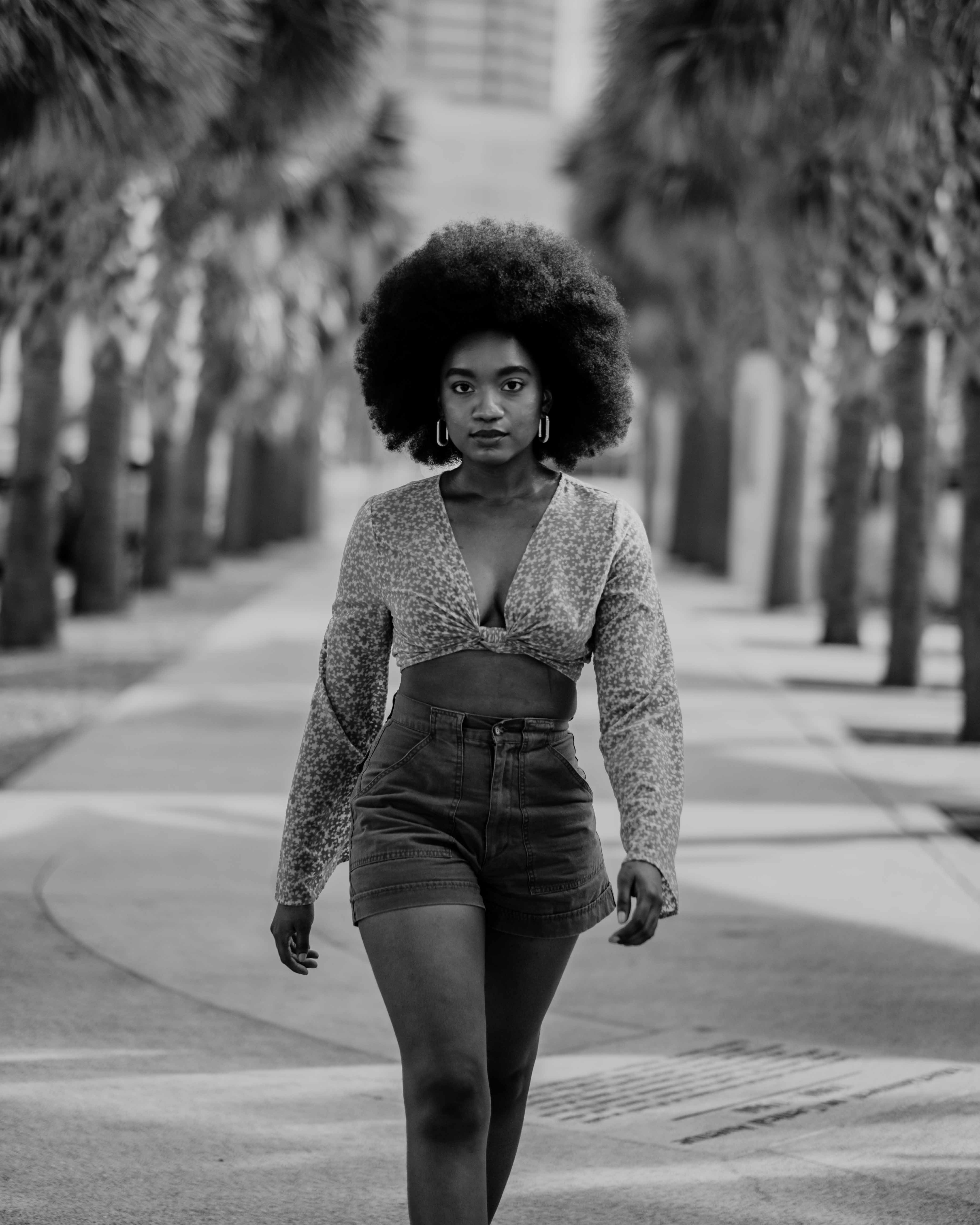 A woman with an afro walking down a street · Free Stock Photo