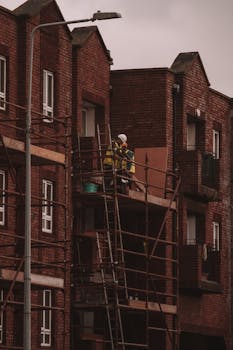 Workers renovating a brick residential building with scaffolding in urban Dublin, Ireland.