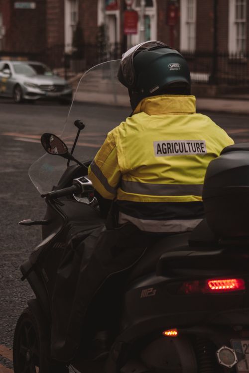 Free Man on motorcycle wearing agriculture jacket rides through Dublin street. Stock Photo