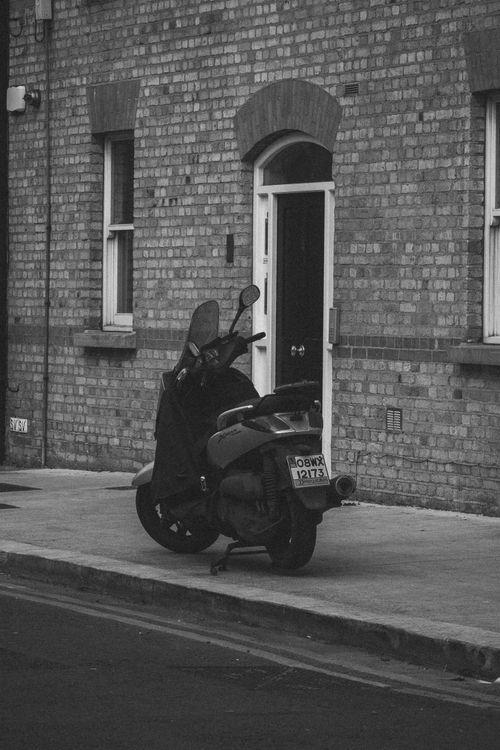Free A black and white photo of a parked scooter on a sidewalk in Dublin, Ireland. Urban setting. Stock Photo