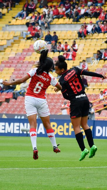 Fotomural Dos jugadoras de fútbol en acción durante un partido, mostrando atletismo y deportividad.