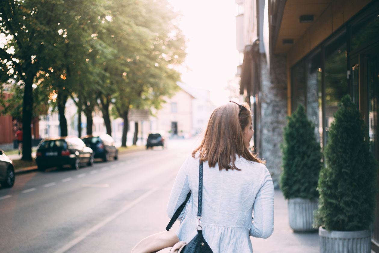 A woman walking along a quiet city street in daylight