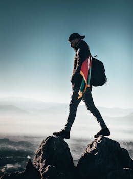 A solitary hiker with a backpack and flag walking atop rocks in the Afghan mountains.