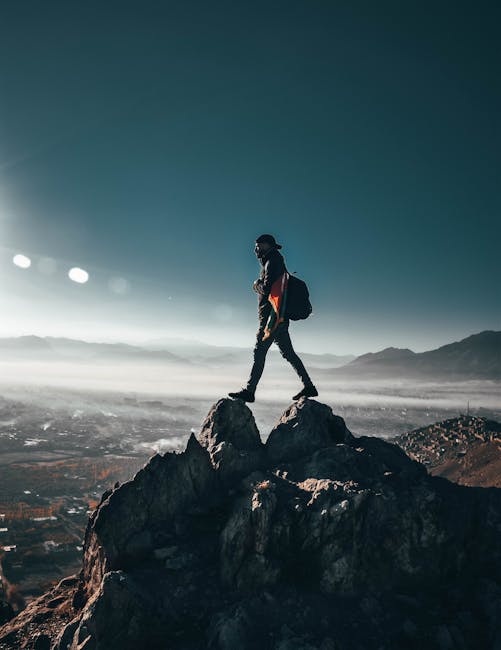 A lone hiker conquering rocky peaks in Nawur, Afghanistan under a clear sky.