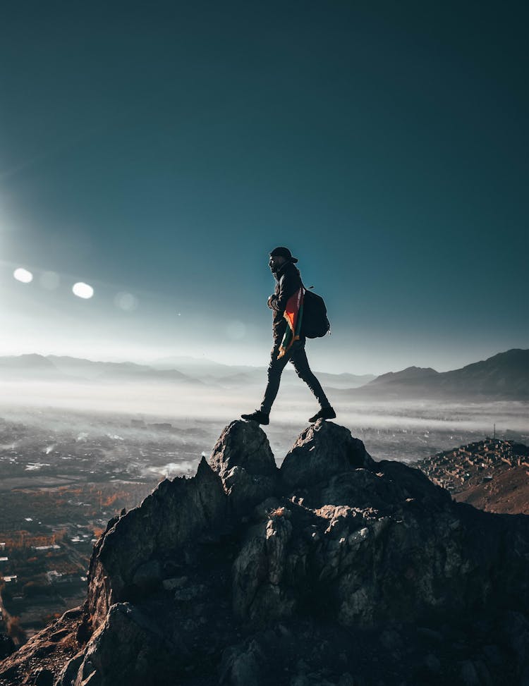 Person Standing On Top Of Rock