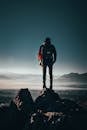 Man Carrying Backpack Standing on Rock Formation