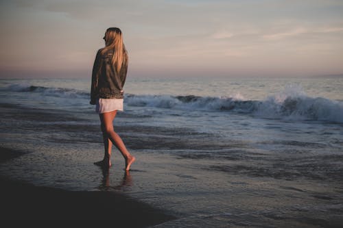 бесплатная Женщина, идущая на берегу моря Стоковое фото