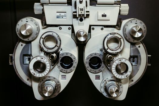 Detailed view of a vintage optometry phoropter with knobs and numbers, showcasing intricate technology.