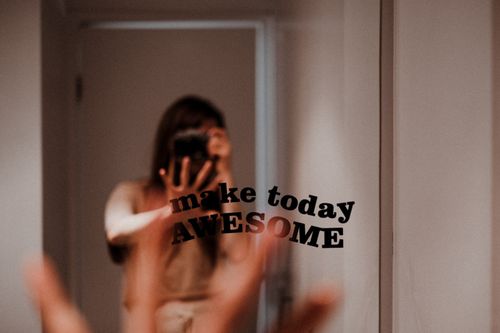 Free Woman photographer capturing her reflection with motivational text on mirror. Stock Photo