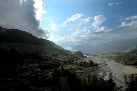 在戏剧性的云层下，郁郁葱葱的水稻梯田和河流穿过山谷，景色壮丽