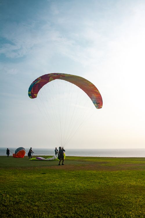 Free Multi-person paragliding adventure on a sunny coastal grassland. Stock Photo