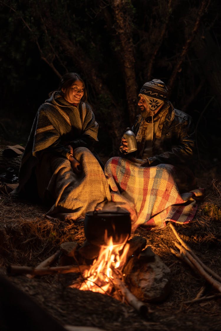 Couple Sitting Near Campfire In Forest