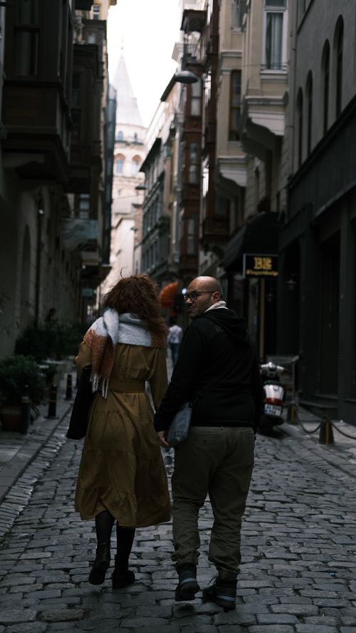 Free Couple strolling along Istanbul's cobblestone streets with a view of Galata Tower in the distance. Stock Photo