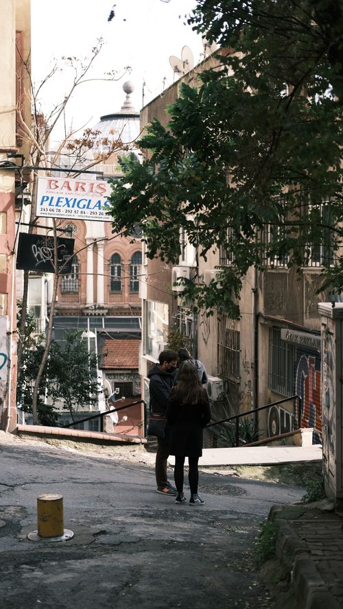 Free Couple walking in a serene urban street, surrounded by historic architecture. Stock Photo