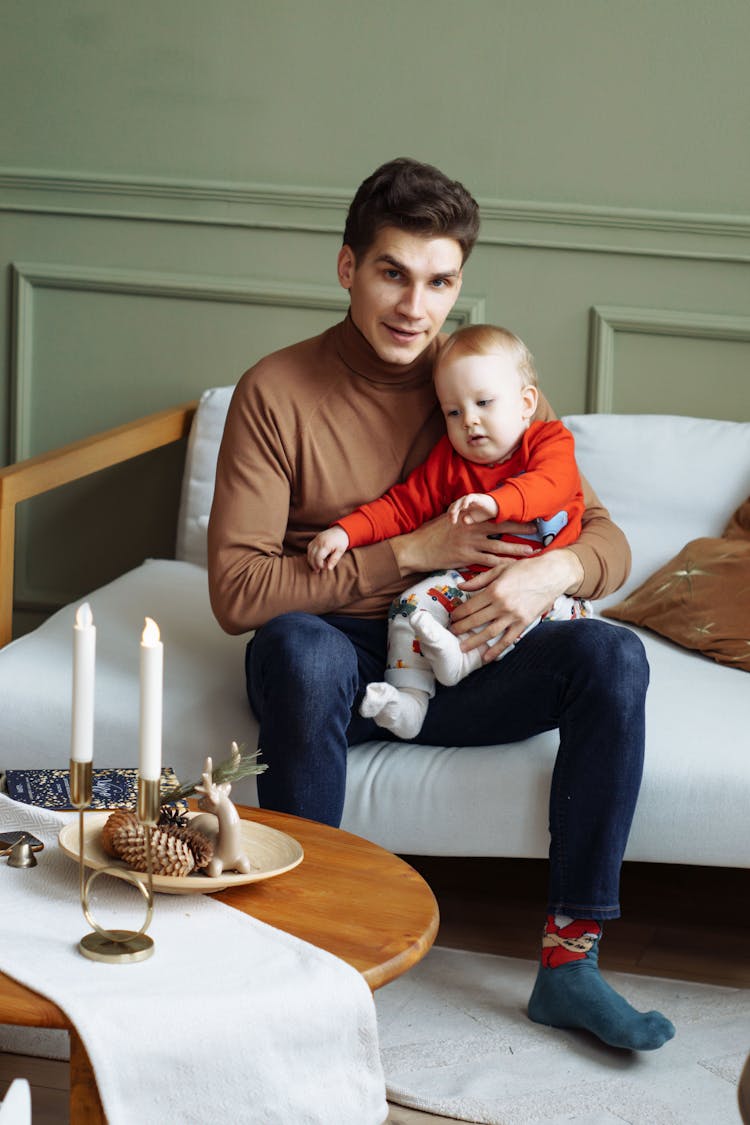 Man Sitting On Sofa With Cute Baby