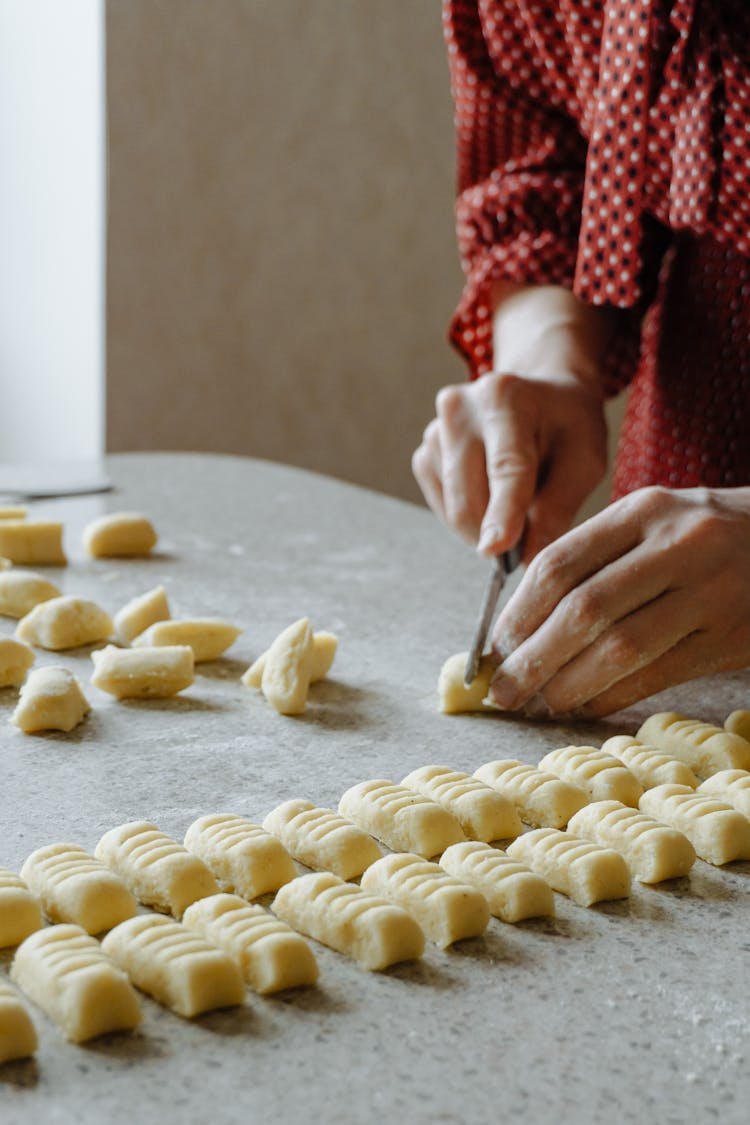 Close-up Of Woman Making Gnocchi On Table