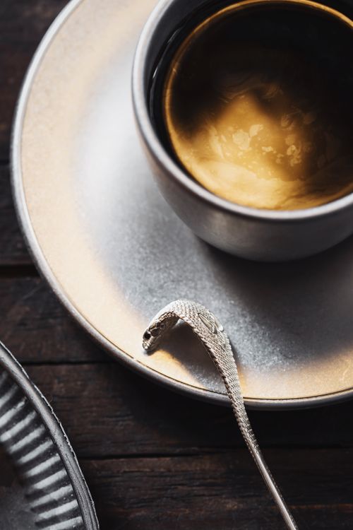 Free An artistic shot of coffee in a cup with a silver spoon on a saucer, highlighting elegance and texture. Stock Photo