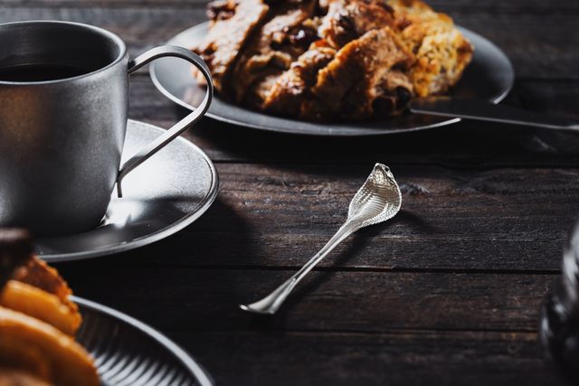 A cup of coffee beside a fruit pastry on a dark wooden table — photo by COPPERTIST WU on Pexels