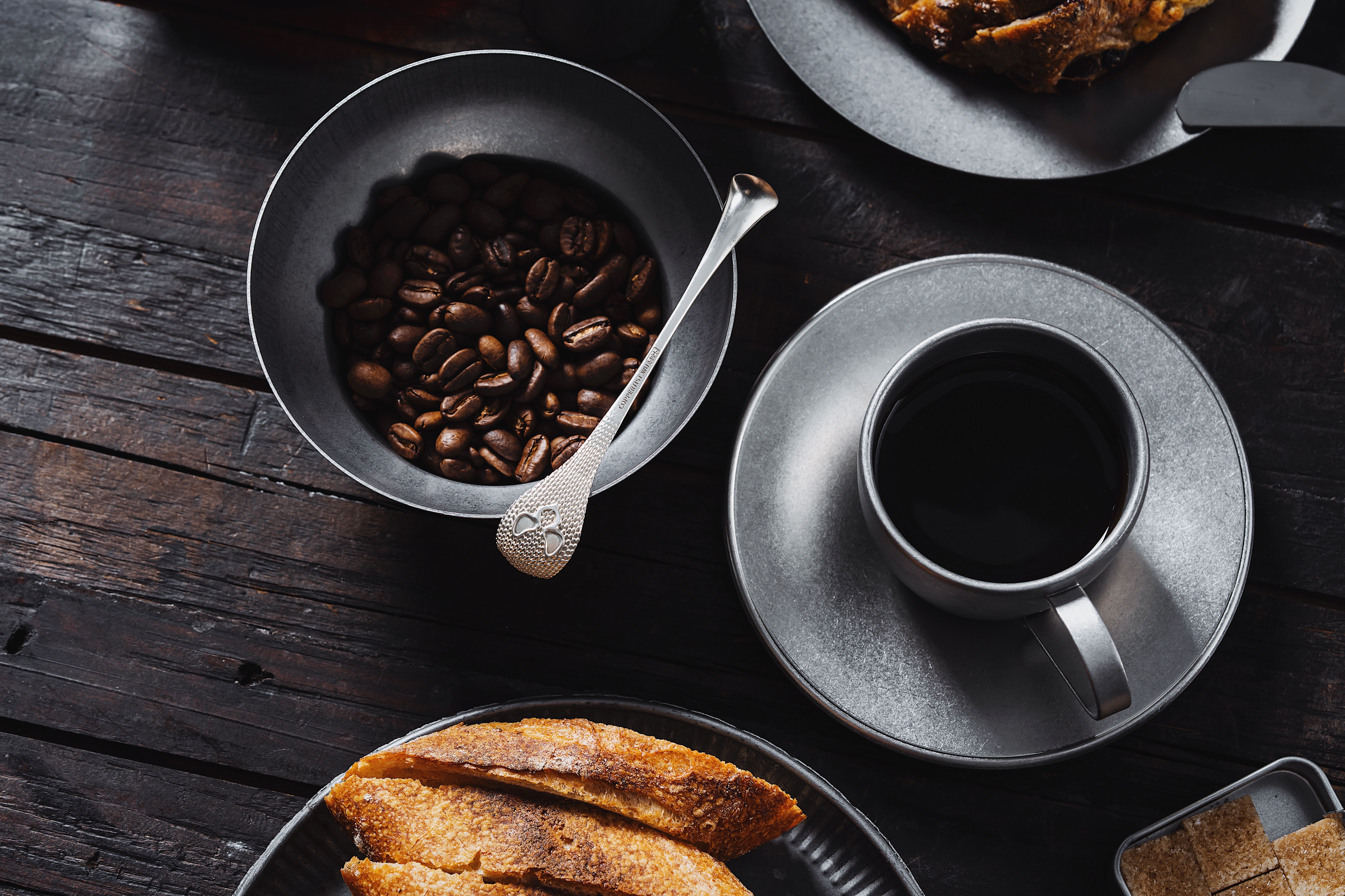 Flat lay of coffee, beans, and pastry on rustic wooden table. Perfect for breakfast visuals.