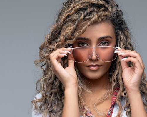 Studio Portrait of a Young Woman with Curly Hair Wearing Sunglasses