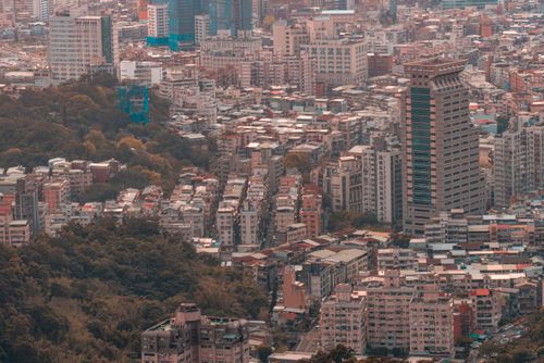 Free Aerial view of a sprawling cityscape showcasing dense urban architecture and surrounding greenery. Stock Photo