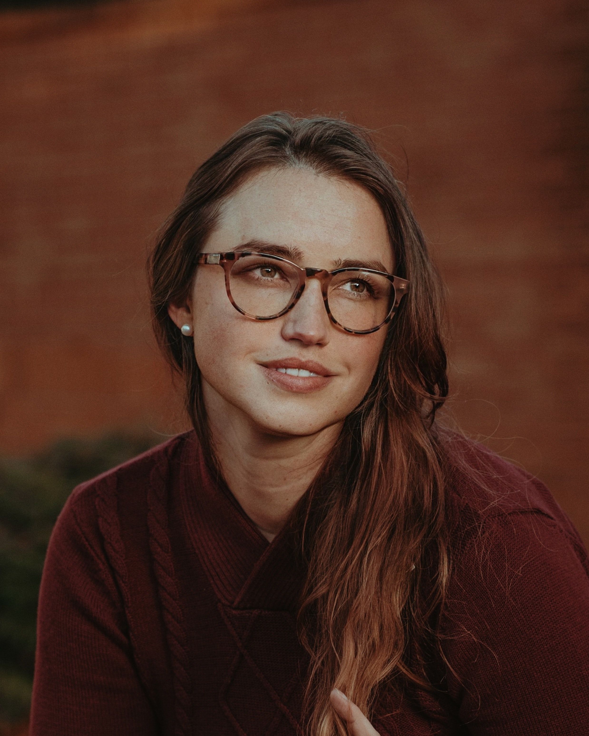 A smiling woman with brunette hair and eyeglasses enjoys a day outdoors in Portland.
