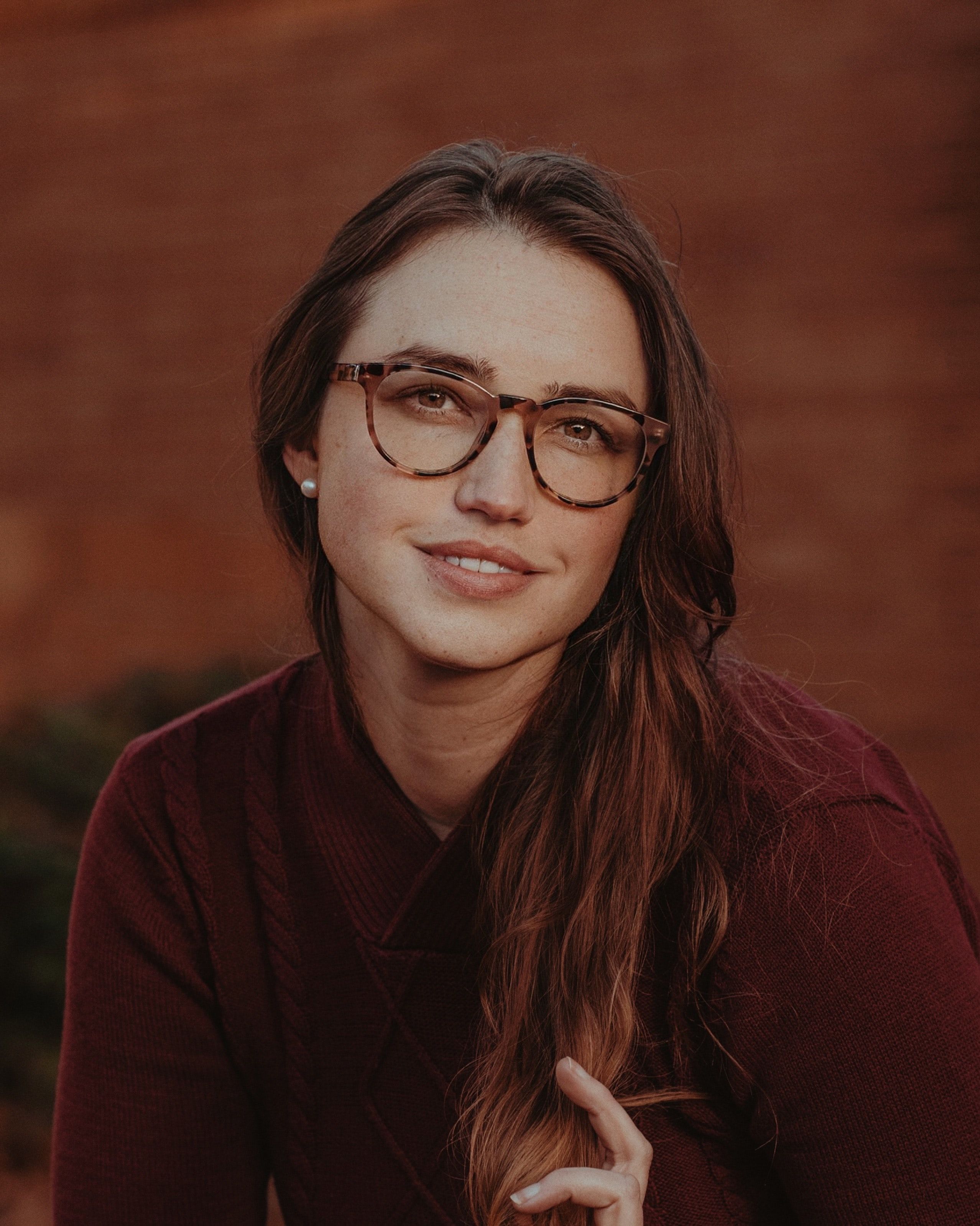 Portrait of a young woman with eyeglasses, smiling and posing outdoors in Portland, Oregon.