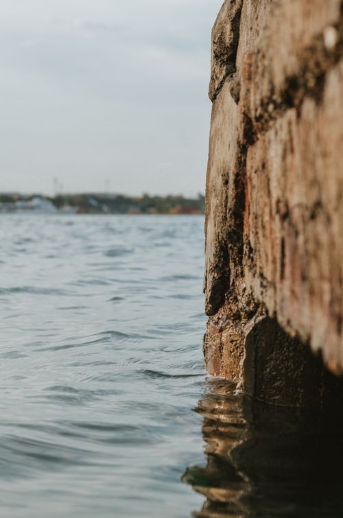 Free Peaceful view of a stone wall against a calm sea under an overcast sky. Stock Photo