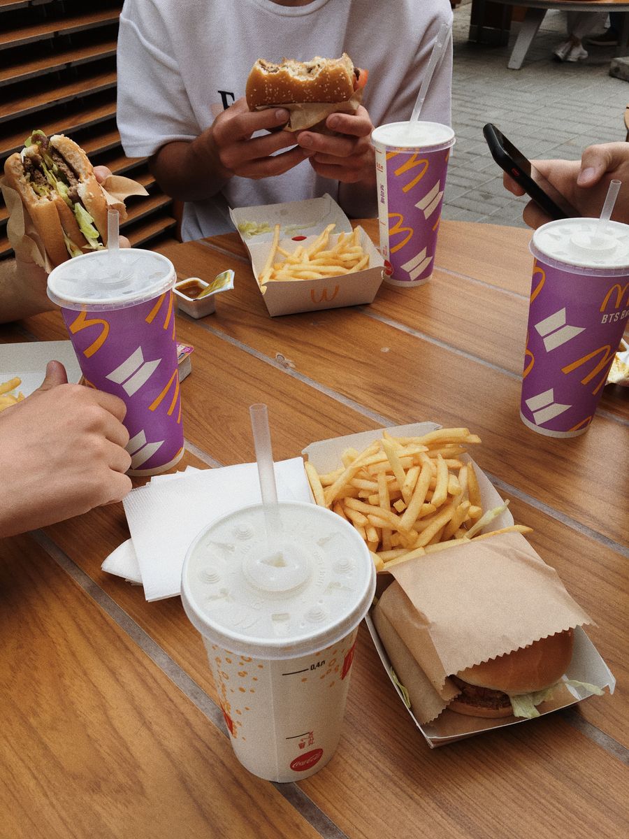 Grupo de amigos reunido à mesa com lanches e bebidas em uma unidade do McDonald's