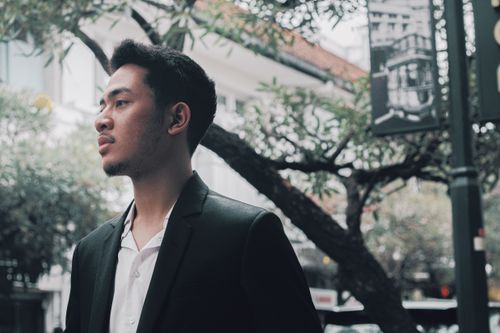 A man in a suit leaning against a wall · Free Stock Photo