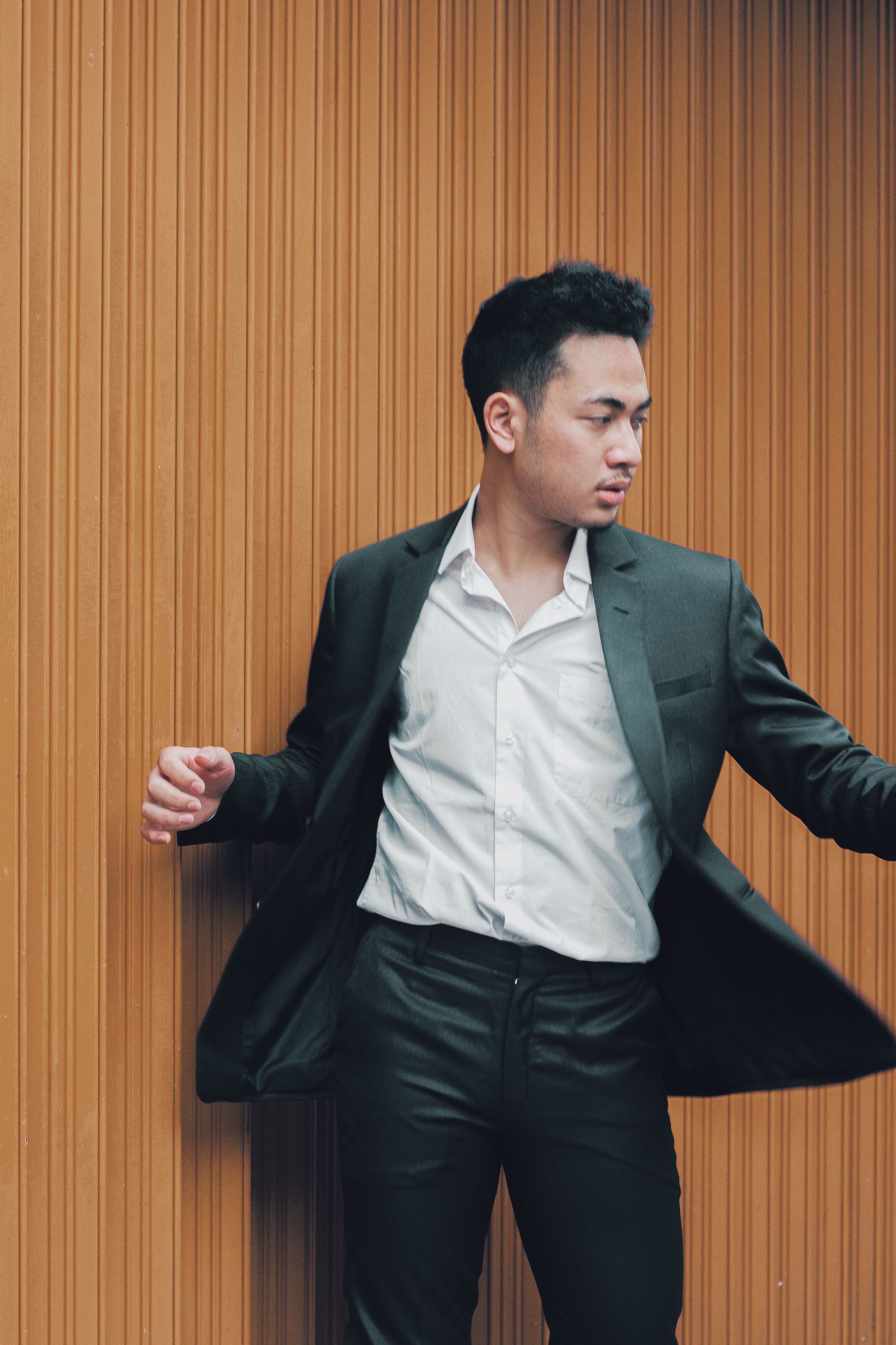 A man in a suit and tie is leaning against a wall · Free Stock Photo