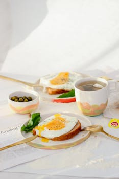 A well-set breakfast featuring eggs on toast, tea, and olives on a bright morning.