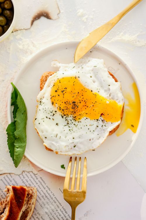 Free Top view of a perfectly cooked fried egg on toast, garnished with herbs. Stock Photo