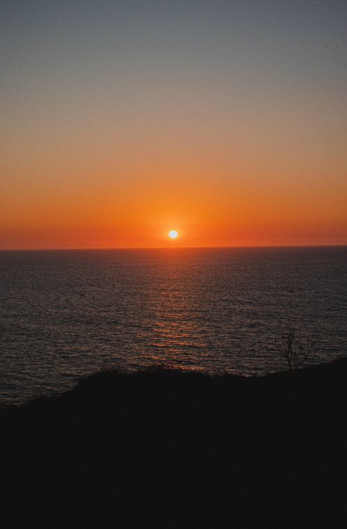 Free A tranquil view of the sun setting over the calm sea and horizon. Stock Photo