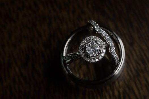 Close-up of a diamond engagement ring set against a dark wooden background, showcasing luxury.