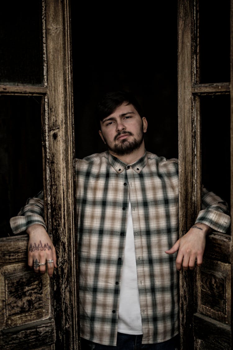 Man In A Plaid Shirt Standing In The Doorway